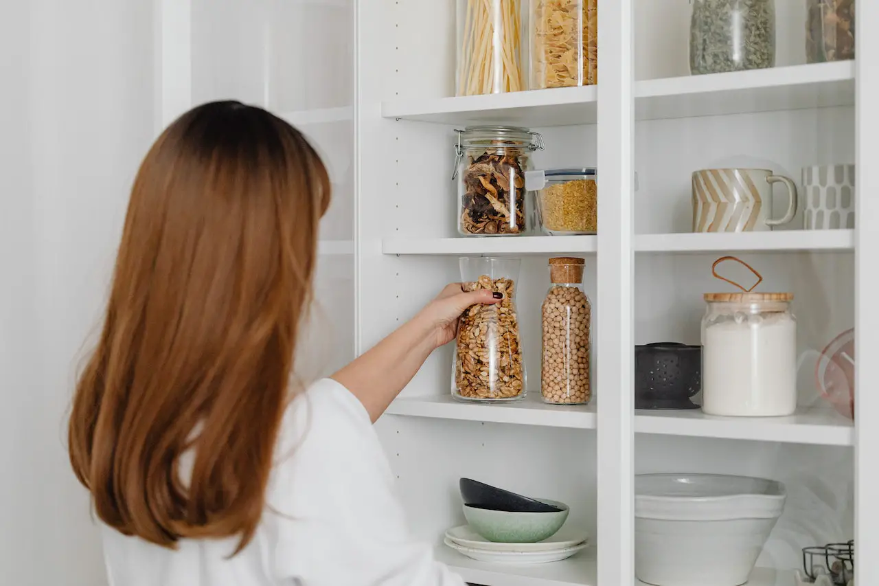 a woman organizing a shelf, one of the kitchen storage solutions